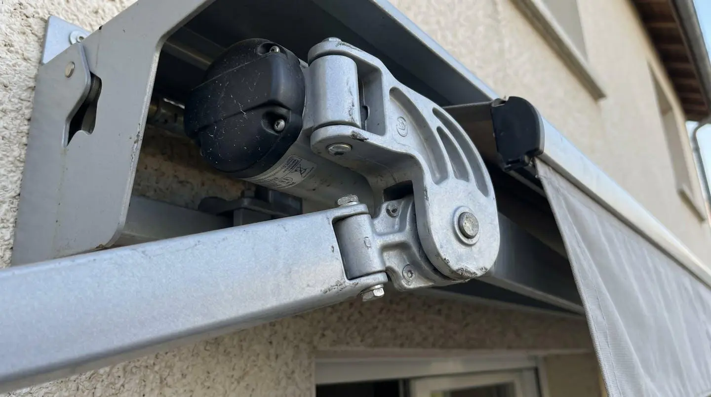 Gros plan détail mécanisme bras articulé de store banne en aluminium avec jonction motorisée